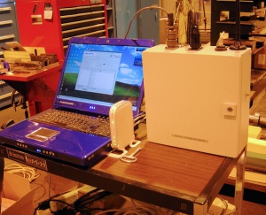 A computer and a white box on a tableDescription automatically generated